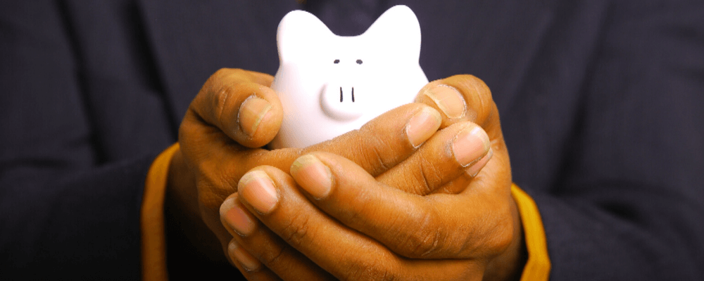 A man's hand is holding a piggy bank.