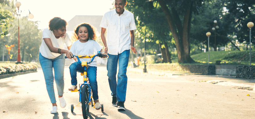Parents teaching kid to ride a bike